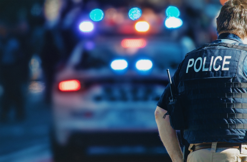 A police officer's back with a cop car in the background